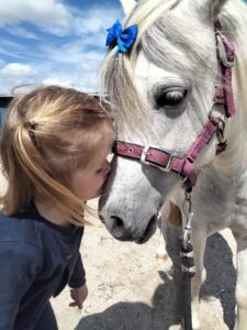 La thérapie avec le cheval permet de développer les émotions et l'attachement. Ici une petite fille qui embrasse son poney. Le Poney est très attentif à elle.